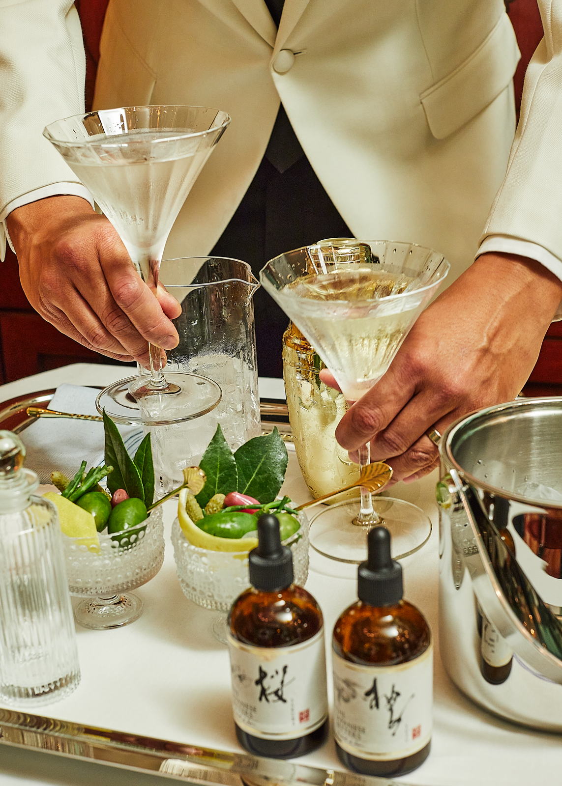 A waiter sets the table with cocktail glasses and welcome dishes for the guests.