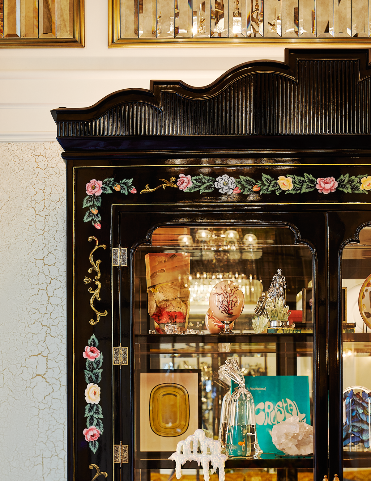 An elegant, dark wooden display cabinet featuring intricate floral decorations on the borders.